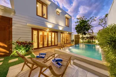 a backyard with a pool and chairs and a house at Freshly Renovated 3 BD Homey Central Villa in Seminyak