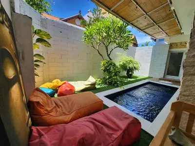 a backyard with a swimming pool with bean bags at Capricorn Villa in Seminyak