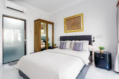 a bedroom with a large bed and a mirror at Villa Putih Jimbaran in Jimbaran