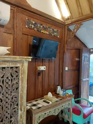 a dining room with a table and a tv at Buratwangi Joglo House in Kerobokan