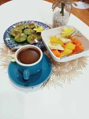 a plate of vegetables and a cup of coffee on a table at Buratwangi Joglo House in Kerobokan