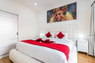 a white bedroom with a large bed with red pillows at Luxury minimalist villa Nobu in Seminyak in Seminyak