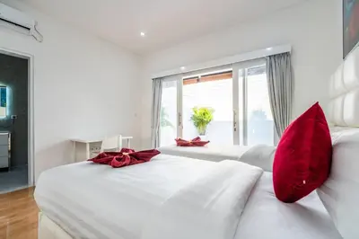 a white bedroom with red pillows on a white bed at Luxury minimalist villa Nobu in Seminyak in Seminyak