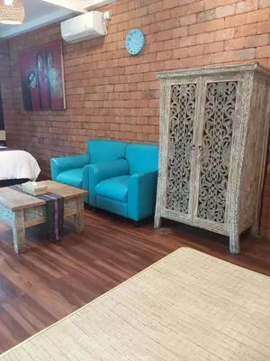 a living room with a blue couch and a brick wall at Buratwangi Tropis House in Kerobokan