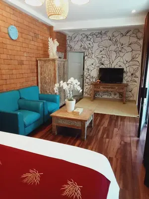 a living room with a blue couch and a tv at Buratwangi Tropis House in Kerobokan