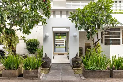 a white house with trees in front of it at Kerta Rama Seminyak by Kerta Living in Seminyak