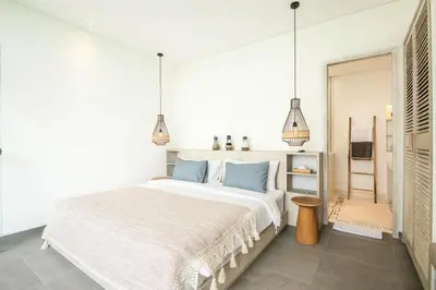 a white bedroom with a large bed with blue pillows at Chic 4BR Villa, Canggu Hub, 800m to Beach Bliss in Canggu