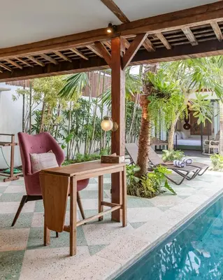 a patio with a table and a chair next to a pool at Villa Gambar - Comfortable Modern Mix 3BR Villa with Large Private Pool, 10 Minutes to the Beach in Canggu