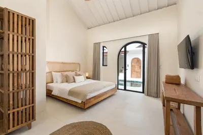 a bedroom with a bed and a tv on a wall at Casa Adem - Modern & Trendy 3BR Villa in Seminyak, 10 Minutes to the Beach with Private Pool in Seminyak