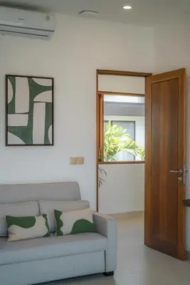 a living room with a couch and a wooden door at Villa Umaju - Contemporary Minimalist 2BR Villa in Umalas! in Canggu