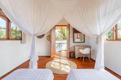 two beds in a room with white curtains at Villa Telma - Charming 2BR Villa in Central Seminyak, Walking Distance to Eat Street in Seminyak