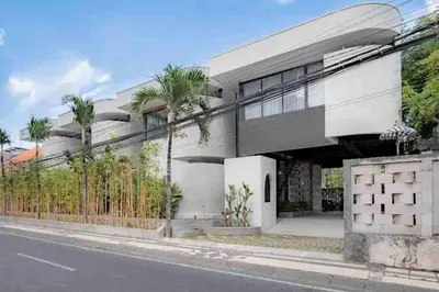 a white building with palm trees in front of it at The Drupadi Apartments Studio Peka in Seminyak