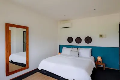 a bedroom with a large white bed and a mirror at House Sawah - Beautiful & Stylish 3BR Home with Jacuzzi Near Umalas and Seminyak in Kerobokan