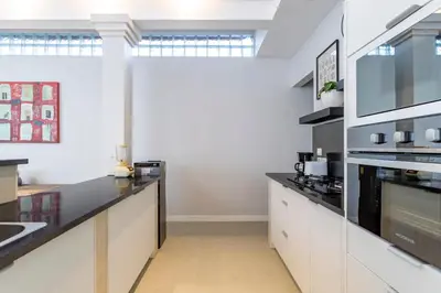 a kitchen with white cabinets and black counter tops at Villa Elea - Bright & Modern 2BR Villa in Seminyak with Private Pool and Sunset Rooftop in Seminyak