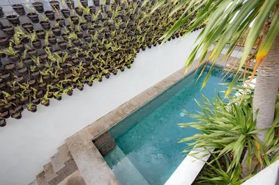 a swimming pool with plants on the side of a building at Town House REX in Kuta