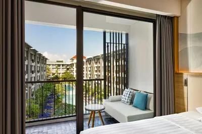 a bedroom with a balcony with a bed and a couch at Courtyard by Marriott Bali Seminyak Resort in Seminyak