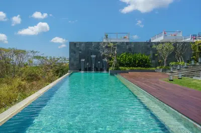 a swimming pool with blue water in front of a building at Beyond The Sea - Luxe Sea View Villa in Jimbaran in Jimbaran