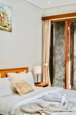 a bedroom with a white bed and a window at Exclusive 2BR Villa with bathroom en suite and privat Pool in Kerobokan