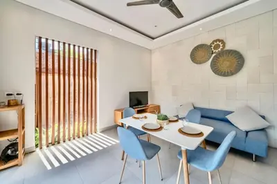 a living room with a blue couch and a table and chairs at Exclusive 2BR Villa with bathroom en suite and privat Pool in Kerobokan