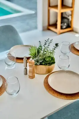 a table with plates and glasses and a potted plant at Exclusive 2BR Villa with bathroom en suite and privat Pool in Kerobokan