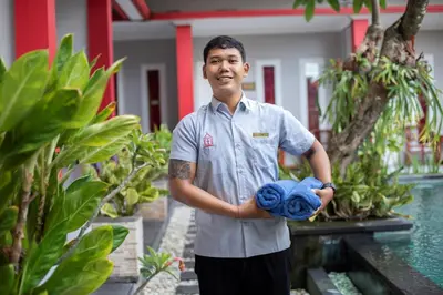a man standing in a garden holding towels at Angkul Angkul Beach Inn Kuta by Kamara in Kuta