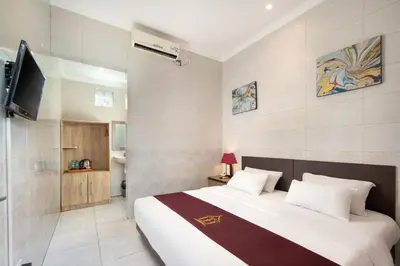 a bedroom with a large bed and a television at Angkul Angkul Beach Inn Kuta by Kamara in Kuta