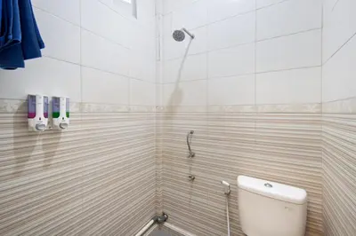 a bathroom with a shower with a toilet at Angkul Angkul Beach Inn Kuta by Kamara in Kuta