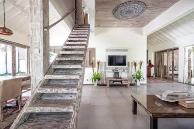 a wooden staircase in a living room with a table at Villa Oberoi in Seminyak