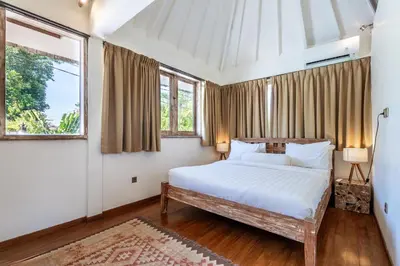 a bedroom with a bed and two windows at Villa Oberoi in Seminyak