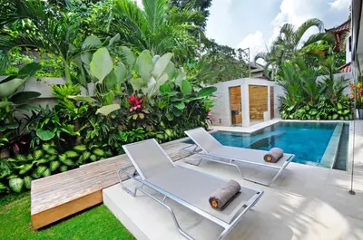 a patio with two chairs and a swimming pool at 4BR Villa Minggu - Minggu Villas Seminyak in Seminyak