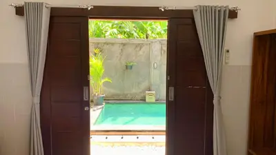 an open door leading to a swimming pool with a window at St.Regina Bali 3 Bedroom Villa in Nusa Dua