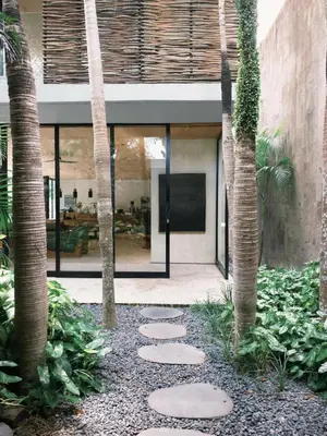 a courtyard with palm trees and stepping stones at Sandhouse Berawa in Canggu