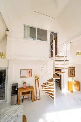 a white living room with a spiral staircase and a desk at Spacious 3 BR Villa with private pool and Billiards in Seminyak