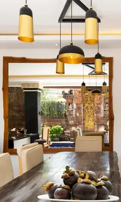 a dining room with a wooden table and lights at Winy Estate - Luxury Villa with Rooftop Jacuzzi in Canggu