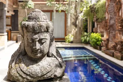 a statue next to a pool in a yard at Winy Estate - Luxury Villa with Rooftop Jacuzzi in Canggu