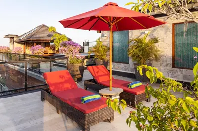 a patio with two chairs and an umbrella at Winy Estate - Luxury Villa with Rooftop Jacuzzi in Canggu