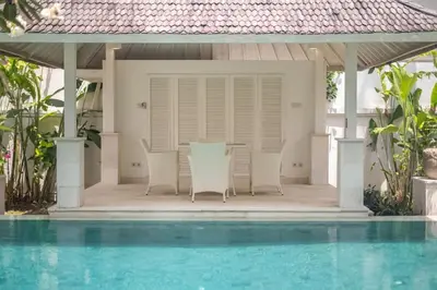 a villa with a swimming pool next to a house at Beachside Colonial Elegance: 4BR in Canggu in Canggu