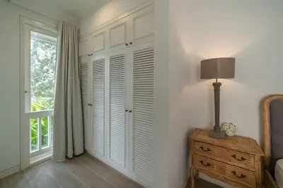 a bedroom with white walls and a window and a lamp at Beachside Colonial Elegance: 4BR in Canggu in Canggu