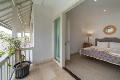 a bedroom with a bed and a balcony at Beachside Colonial Elegance: 4BR in Canggu in Canggu