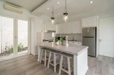 a kitchen with white cabinets and a large island with bar stools at Beachside Colonial Elegance: 4BR in Canggu in Canggu