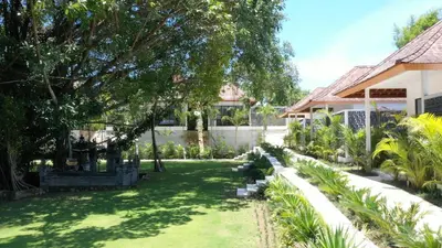 a yard with green grass and a house at Three-Bedroom Pool Villa at Anwa Residences in Canggu