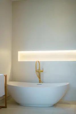 a bathroom with a white tub with a gold faucet at Casa Donilo - 4BR Designer Villa in Canggu in Canggu