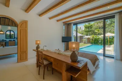a bedroom with a desk and a bed and a pool at Casa Donilo - 4BR Designer Villa in Canggu in Canggu