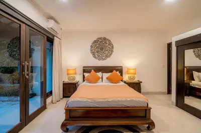 a bedroom with a bed with two lamps and a mirror at Sari Temuku Villa in Seminyak