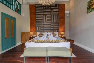 a bedroom with a large white bed with two benches at Mezzanine Industrial 1 Bedroom Private Villa in Seminyak in Seminyak