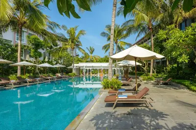 a pool at the resort with lounge chairs and umbrellas at Hilton Garden Inn Bali Ngurah Rai Airport in Kuta