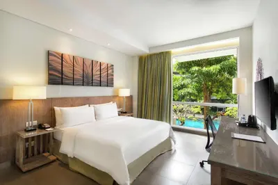 a hotel room with a bed and a large window at Hilton Garden Inn Bali Ngurah Rai Airport in Kuta