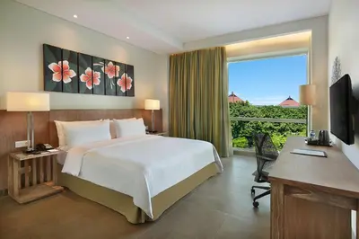 a bedroom with a bed and a desk and a window at Hilton Garden Inn Bali Ngurah Rai Airport in Kuta