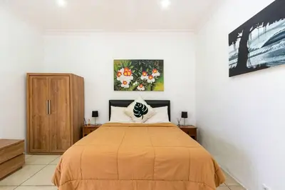 a bedroom with a bed and a painting on the wall at Buddha Beach Villa Seminyak in Seminyak