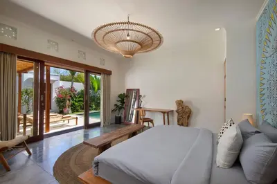 a bedroom with a bed and a couch and a chandelier at Villa Pawikan Gorgeous 4 beds villa in the heart of Seminyak in Seminyak